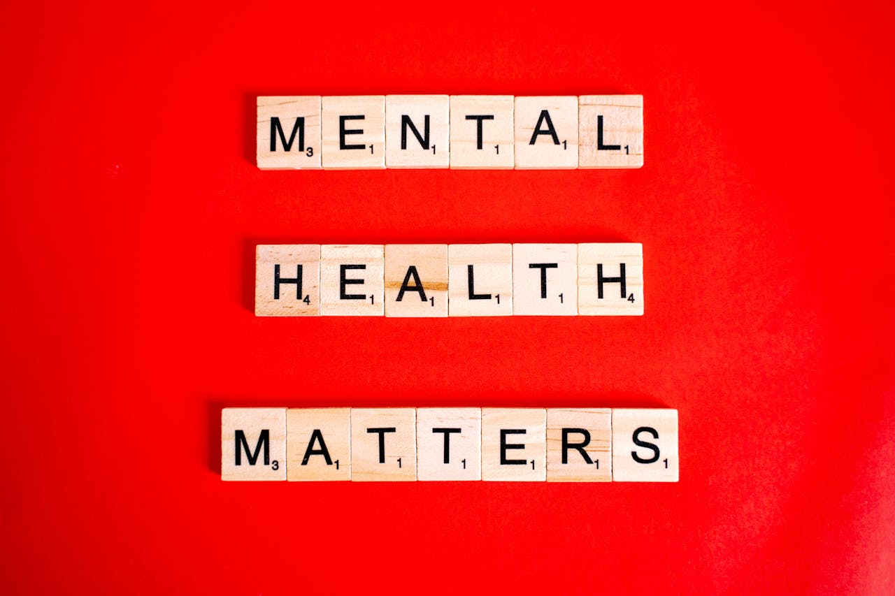 Wooden tiles spelling Mental Health Matters on a vivid red background.